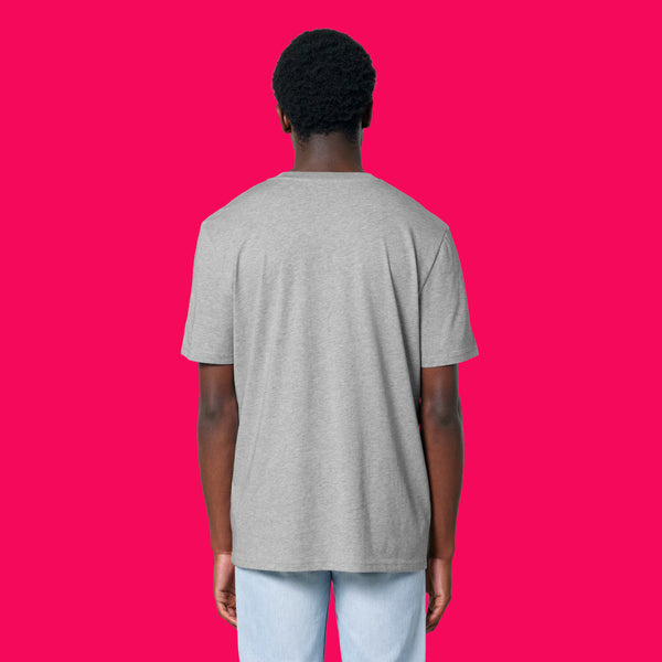 Back view of a model wearing the Wield Your Weird Adults T Shirt by Katie Abey in heather grey. The relaxed fit unisex T shirt is styled with light blue jeans and photographed against a bright pink background.