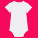 White organic cotton babygrow shown from the back against a bright pink background. Short sleeved baby bodysuit with a smooth plain back, soft rib binding at the neckline and leg openings, and snap fastenings at the bottom for easy changes. Unisex baby clothing suitable for everyday wear.