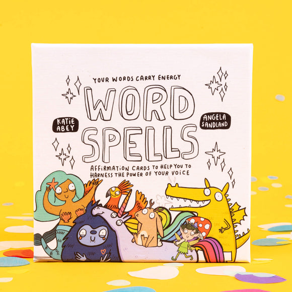 Box of Word Spell Cards on a yellow background with confetti. the box is white with 'your words carry energy' and 'affirmation cards to help you to harness the power of your voice' written on with various illustrations.