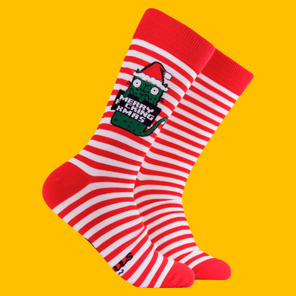Red and white striped Christmas socks featuring Katie Abey’s Sweary Cat character holding a sign that reads “Merry F*cking Xmas”. The socks have red heels and toes, with a fun festive design against a bright yellow background. Quirky Christmas novelty socks from small UK illustrator Katie Abey.