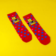 Pack of three sassy cat socks with cat design on polka dot knitted pattern. 76% cotton, 22% polymide, 2% elastane. Yellow cat holding sign that reads 'not funny' on red with blue pink polka dot pattern. Designed by Katie Abey in the UK