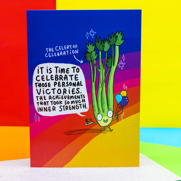 Celery of celebration A6 greeting celebration card happy smiley celery holding balloons and cake on a rainbow background. Designed by Katie Abey in the UK.