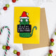  A humorous Christmas card by Katie Abey featuring a green cat wearing a Santa hat and holding a sign that reads "Merry Fucking Christmas" in bold, quirky text. The card has a bright yellow background, contrasting with the festive decorations around it, including candy canes, baubles, and snowflakes. Perfect for those who embrace unconventional humour, this card adds a fun, irreverent twist to holiday greetings, capturing Katie Abey's unique, weirdly wonderful style.