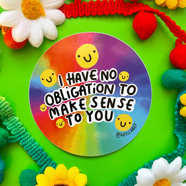 I have no obligation to make sense to you sticker, circular vinyl sticker with rainbow watercolour effect background featuring yellow smiley faces and black and white writing. Designed by Katie Abye in the UK 