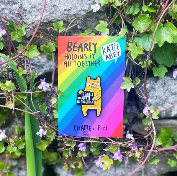 Bearly Holding it All Together soft enamel pin badge in shape of smiley yellow bear with black rubber clasp. Designed by Katie Abey in the UK.