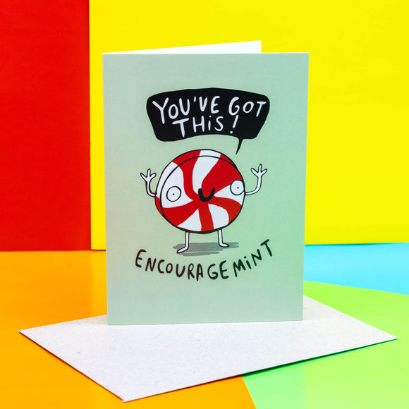 Funny cute A6 blank greeting card reading the pun 'Encouragemint' featuring an illustrated smiley red and white peppermint candy, with speech bubble reading 'You've got this!' on pale green background. Designed by Katie Abey in the UK.