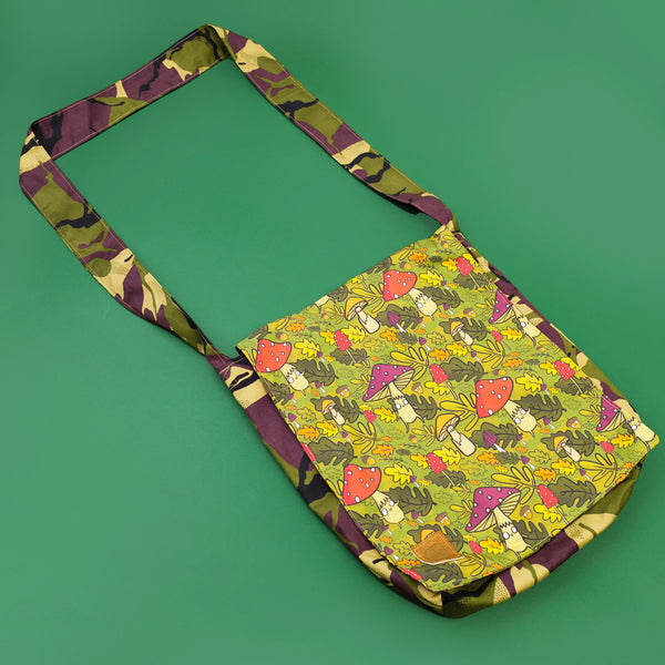Mushroom Bois shoulder bag with green forest illustration featuring smiley mushrooms and acorns, lined with camouflage print fabric and strap. Designed by Katie Abey X Dawney's Sewing Room in the UK
