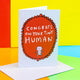 Congrats on your tiny human A6 greeting card designed by Katie Abey and printed in the UK. The card is a white background with a red frilly frame shape with a cartoon white baby and text above that reads 'congrats on your tiny human'. The card is stood up on the brown envelope it comes with on a colourful background.